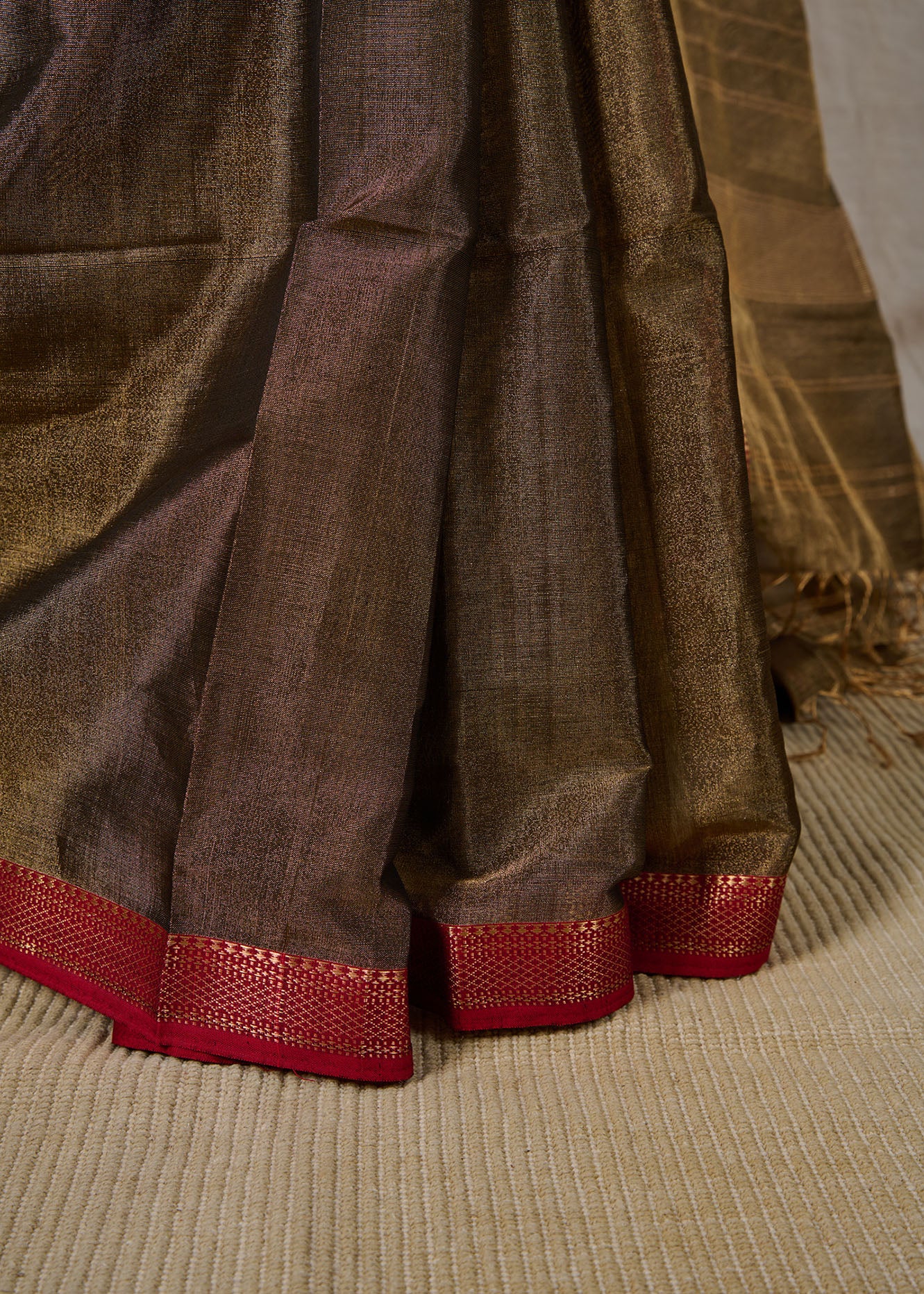 Neat pleats of a maheshwari tissue saree in dual tone of black and gold on showcase.