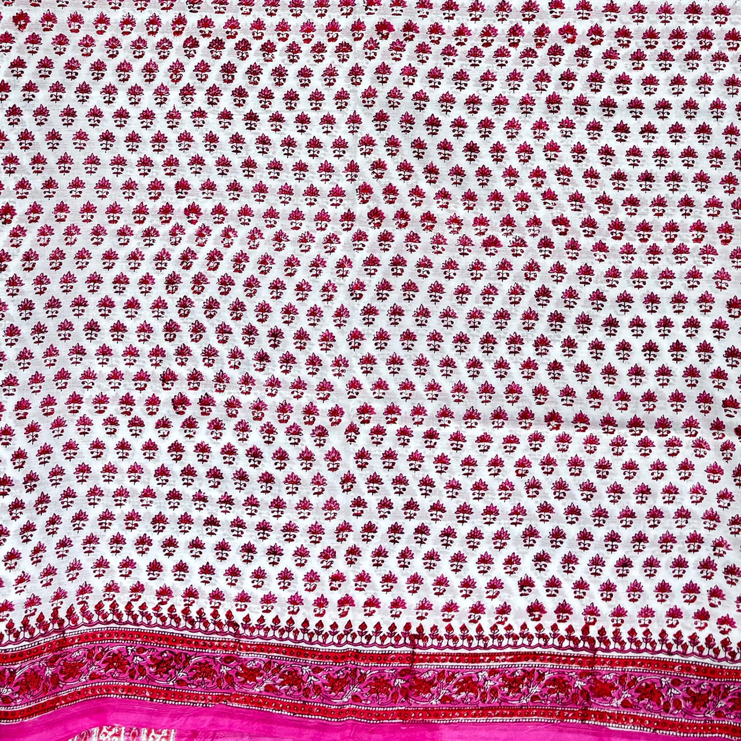 Close up of cotton blockprinted saree with white base and pink and red print.