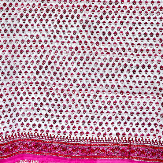 Close up of cotton blockprinted saree with white base and pink and red print.