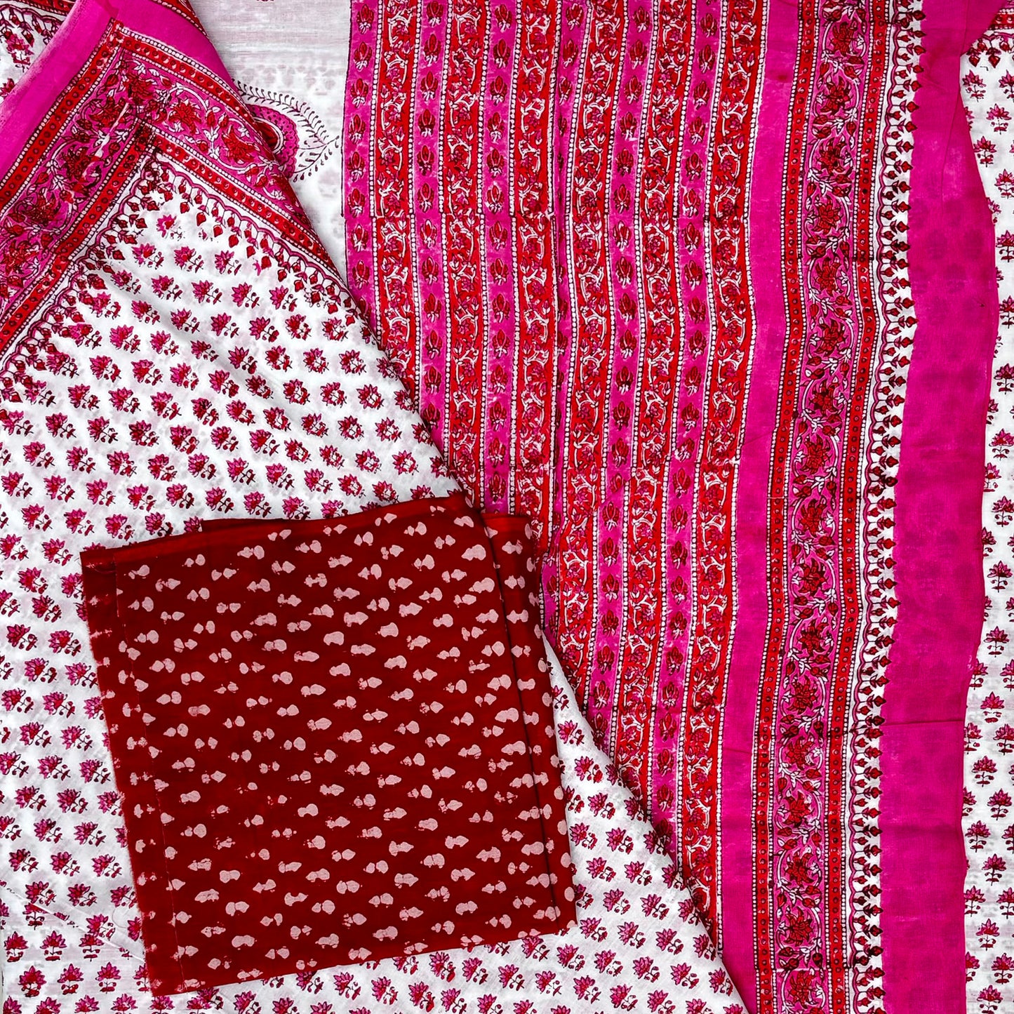 Close up of cotton saree in white base with pink and red floral block printed bootis and contrasting red blouse material with white booti.