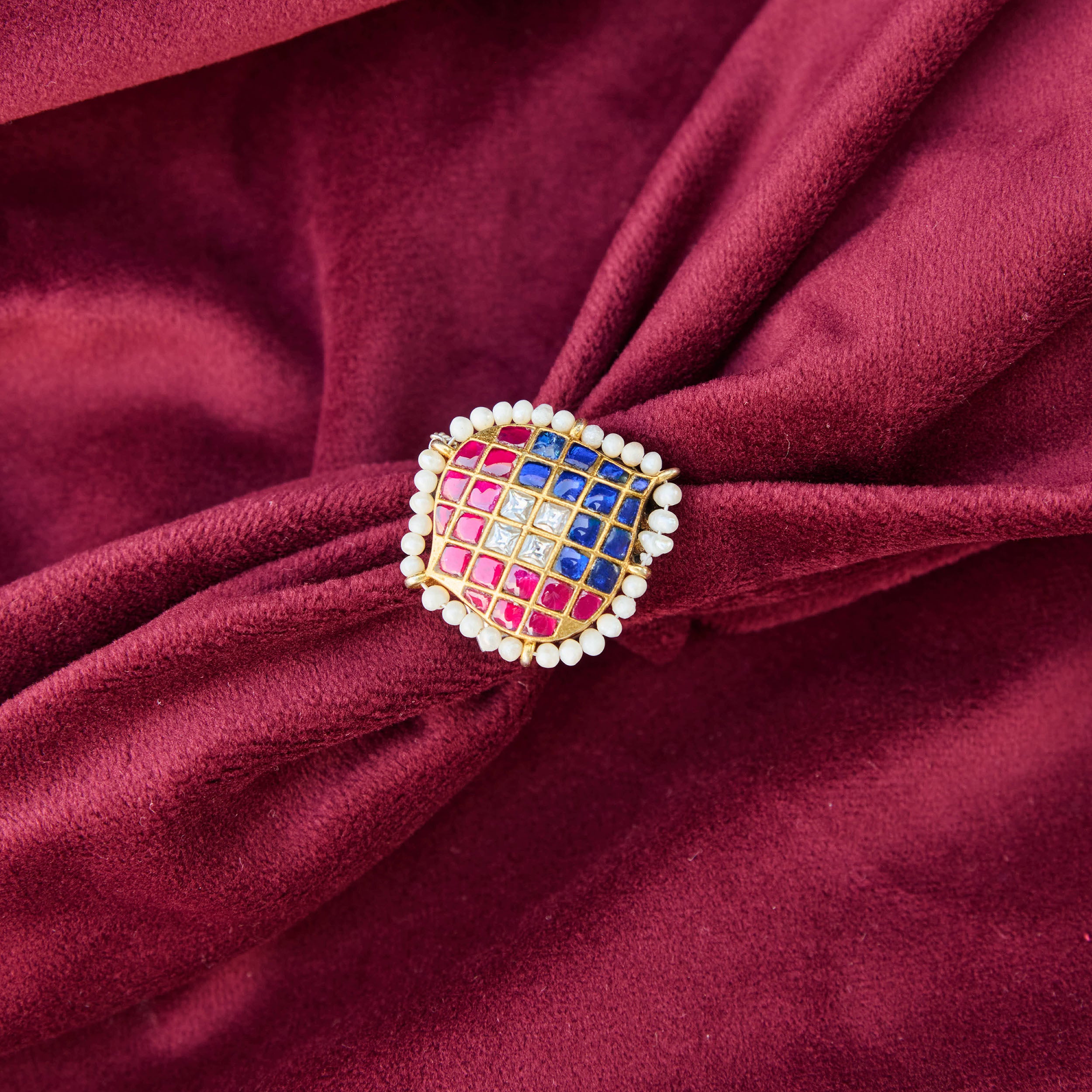 Gold plated silver ring in the shape of a spade rimmed with white pearls and topped with kundan in pink, blue and white stones.
