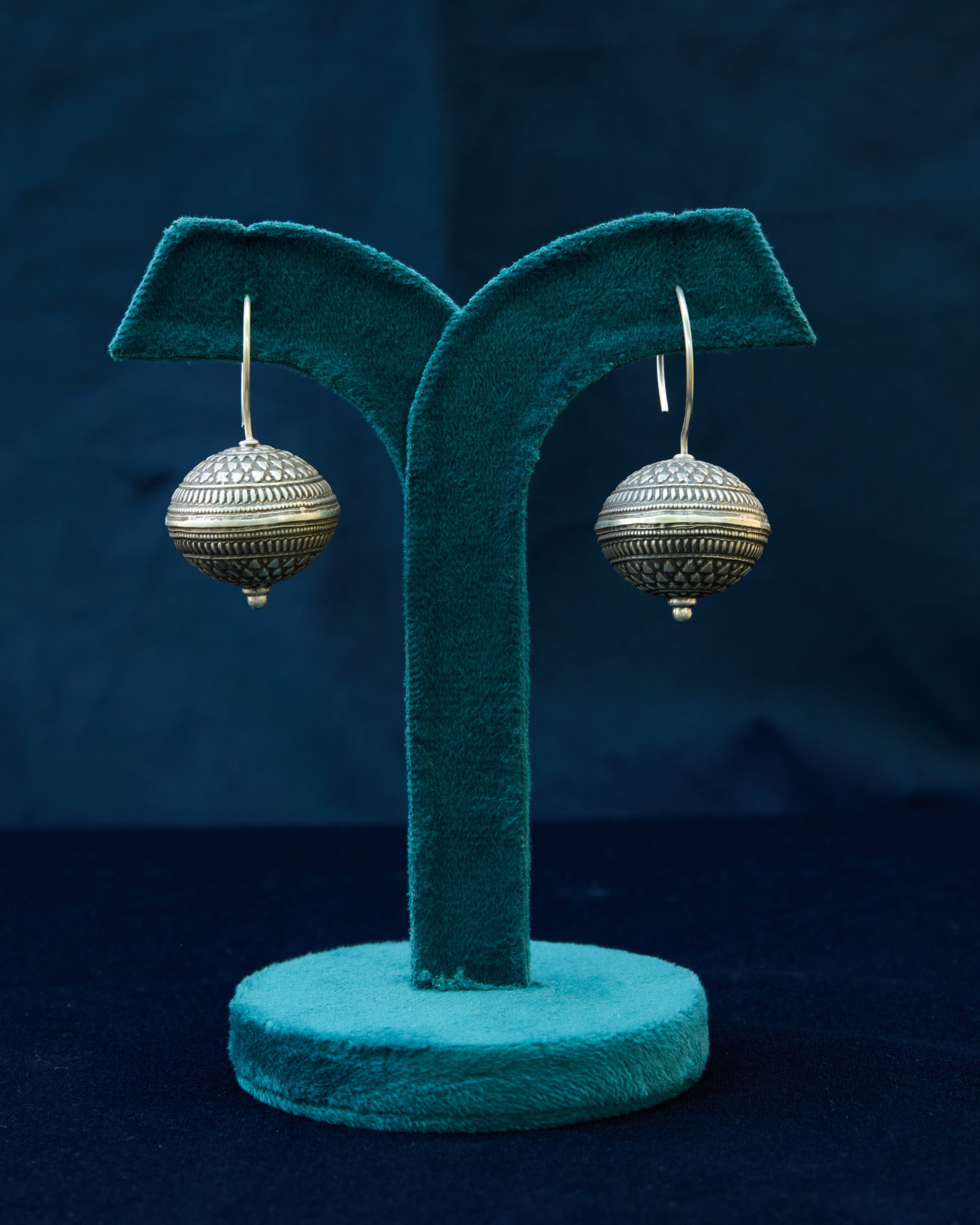 A fish hook earring with a big tribal ball drop suspended from a sturdy silver hook. 