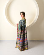 Woman wearing a grey silk bhujodi saree against a white wall