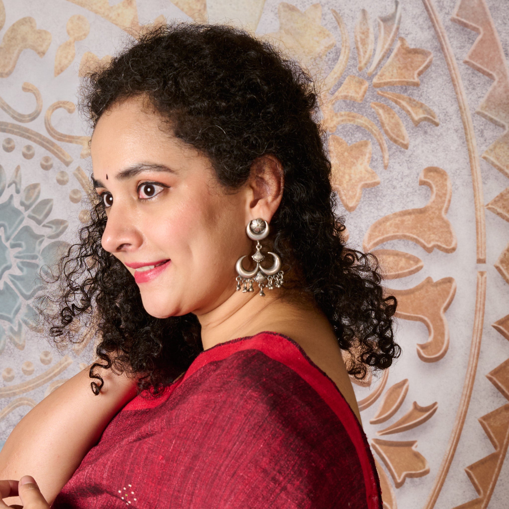 Woman wear a silver earring with half moon shaped chandbaali with tiny ghunrgru. 