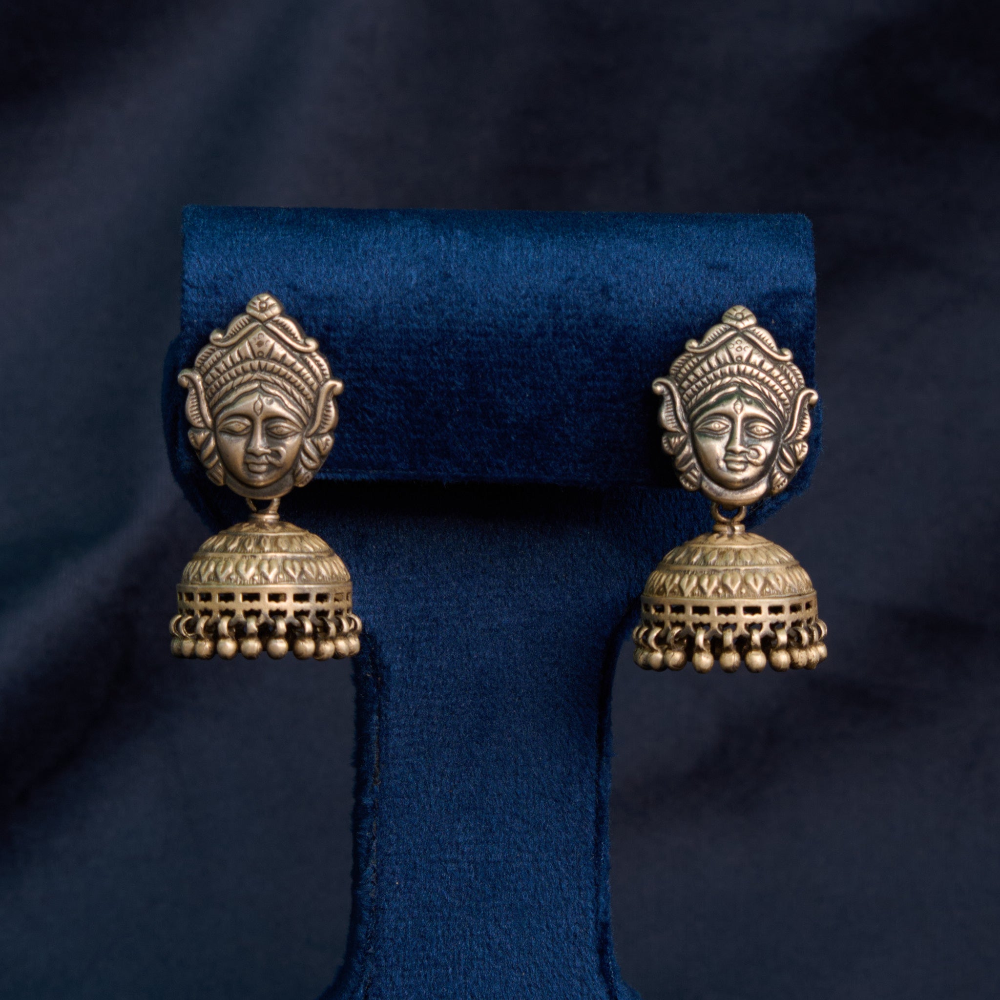 Pair of ornate Durga shakti silver jhumka on blue backdrop