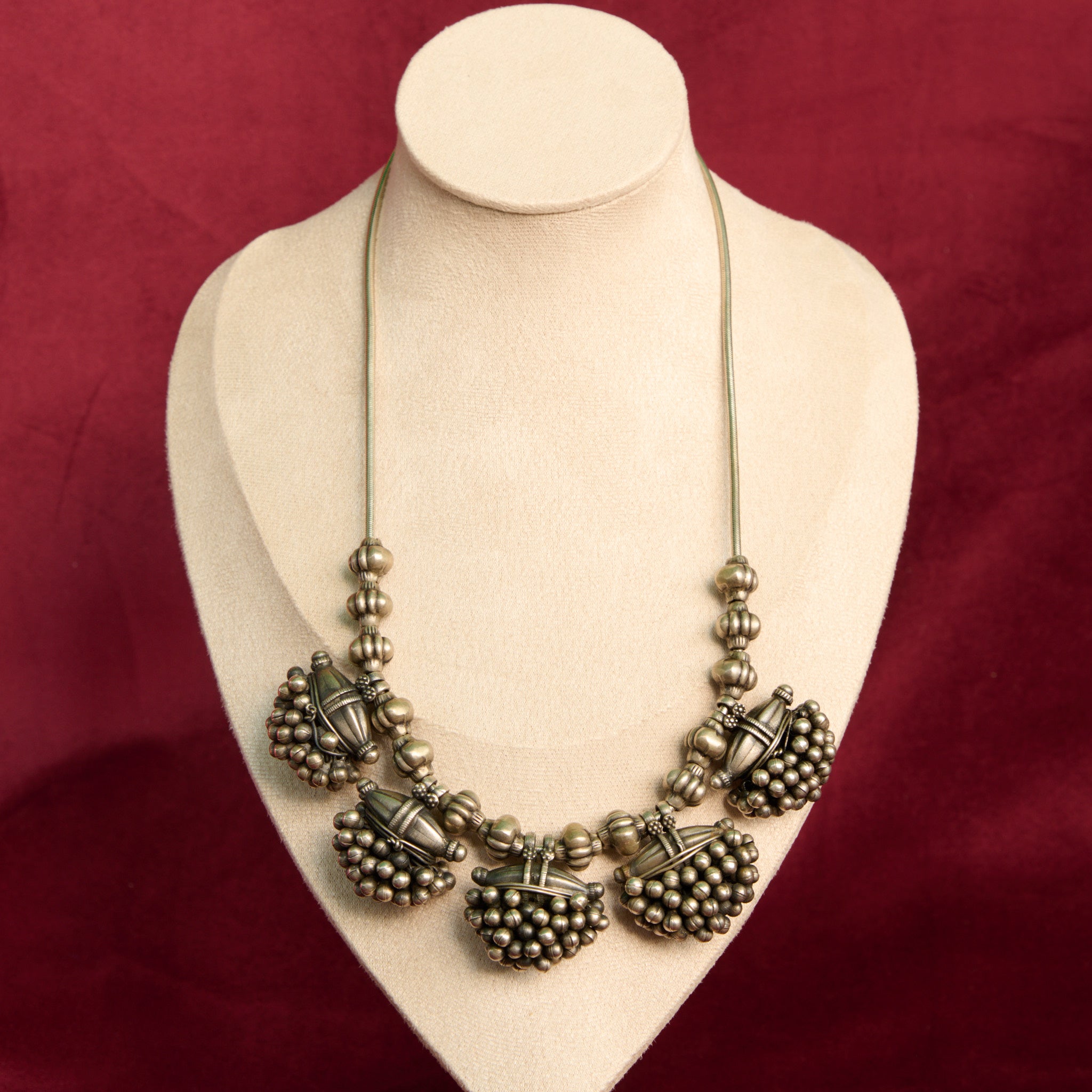 Vintage silver necklace on a mannequin against a red background