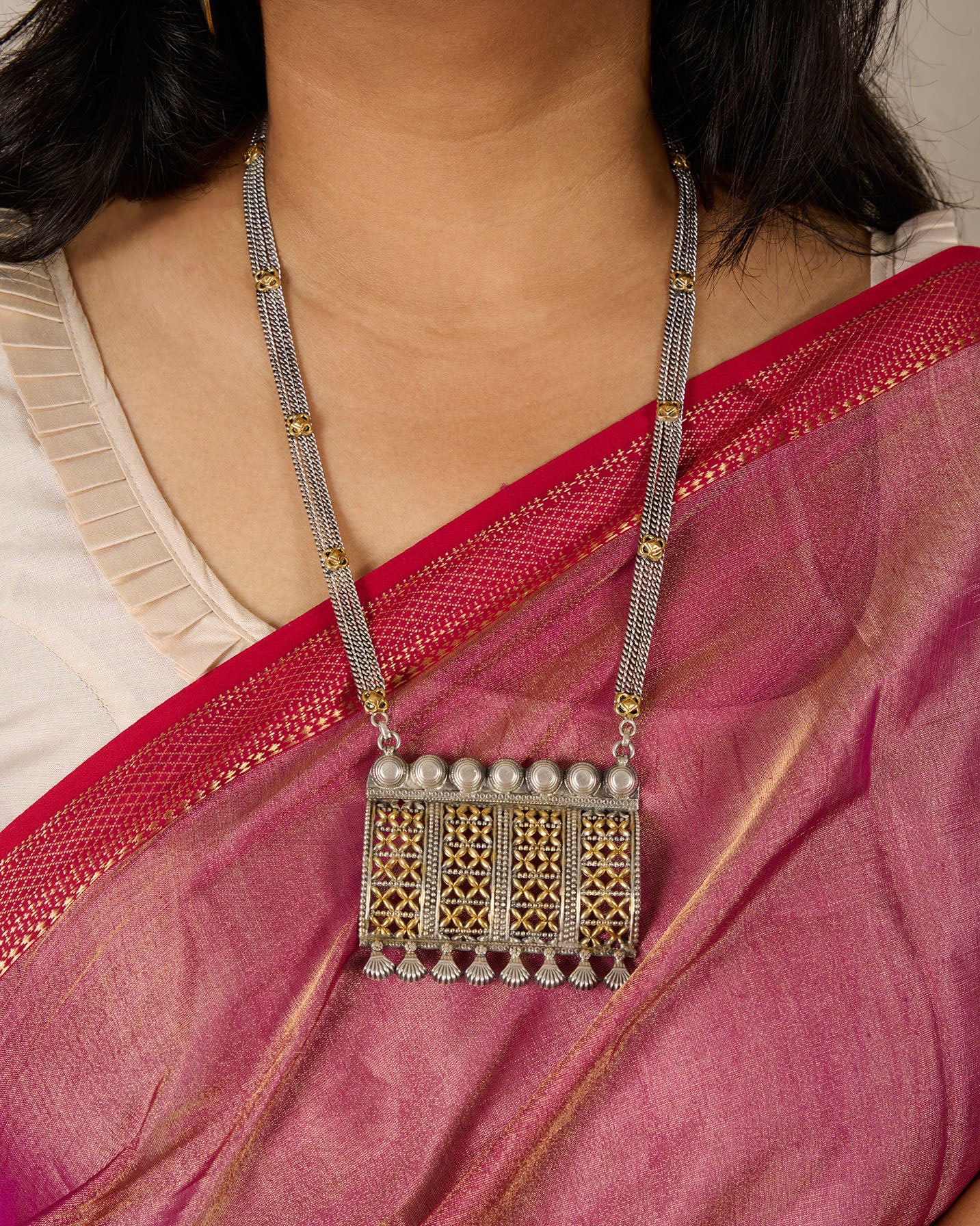 Model wearing saree showcasing a heavy silver necklace with gold polished accents.