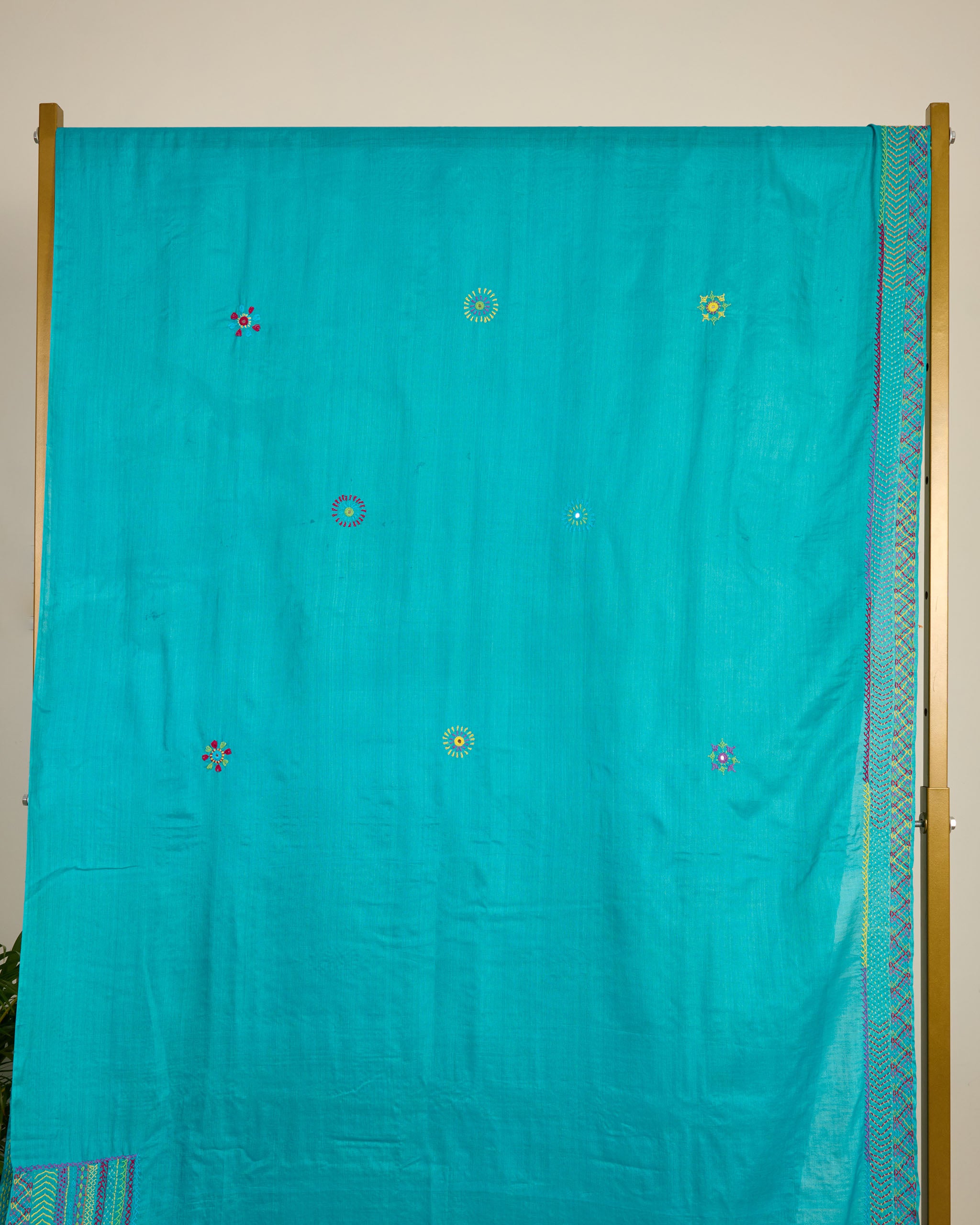 Turquoise blue Kosa silk saree with intricate Lambani embroidery on the border and booti on body of the saree on display.