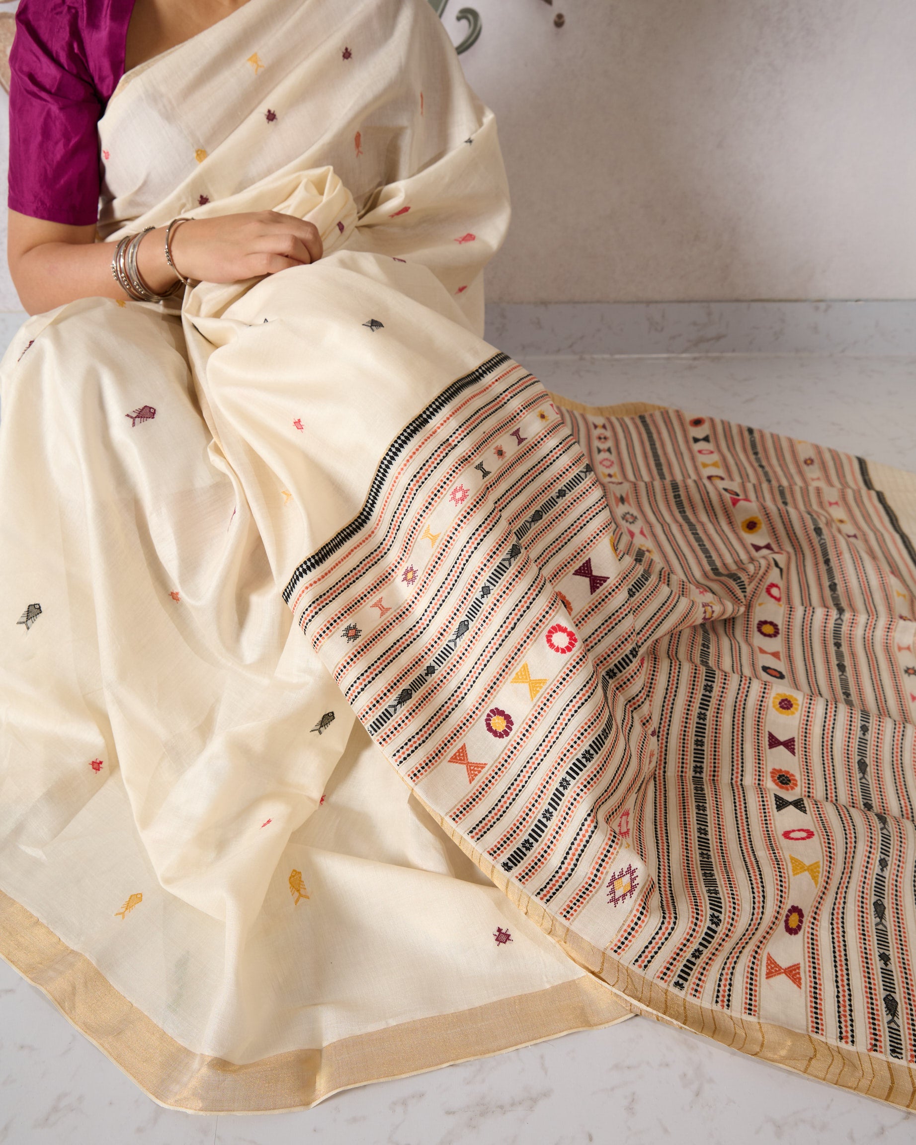 White kosa silk saree with intricate multi colour motifs on a white background
