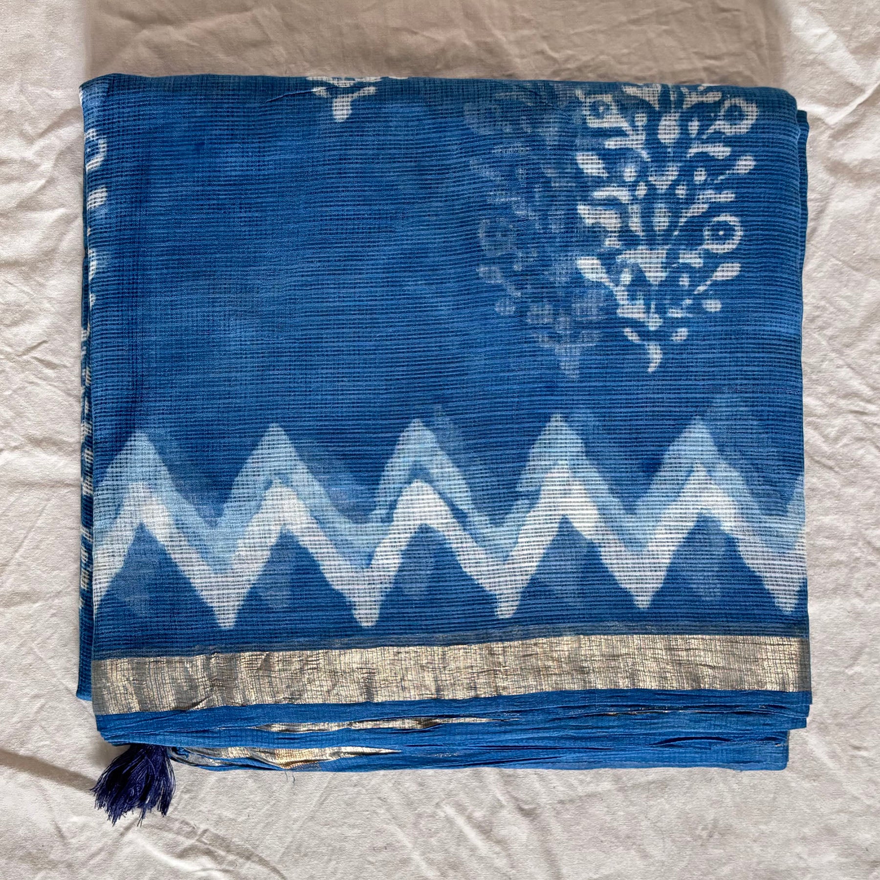 Indigo kota cotton saree with floral dabu booti in the body and zigzag pattern on the border with a thin zari border.