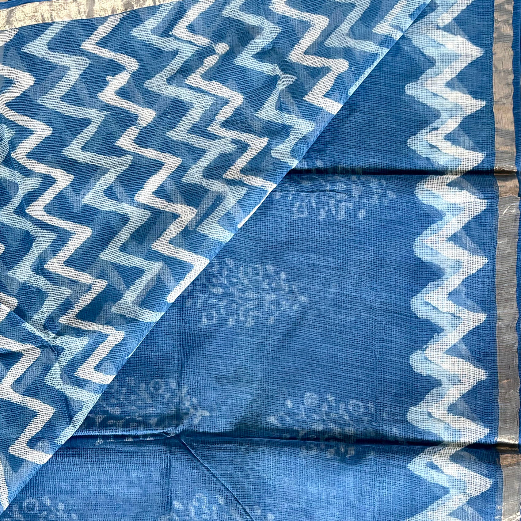 Blouse of the saree is plain indigo with zigzag dabu pattern at the border and thin zari border.
