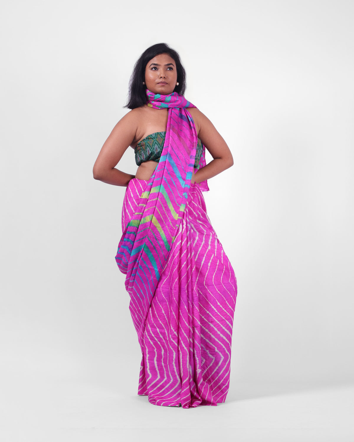 A model is wearing a pink leheriya saree in tussar, the pallu is draped like a stole around her neck. The body of the saree is a pink and white leheriya with a multicolour leheriya on pallu. 
