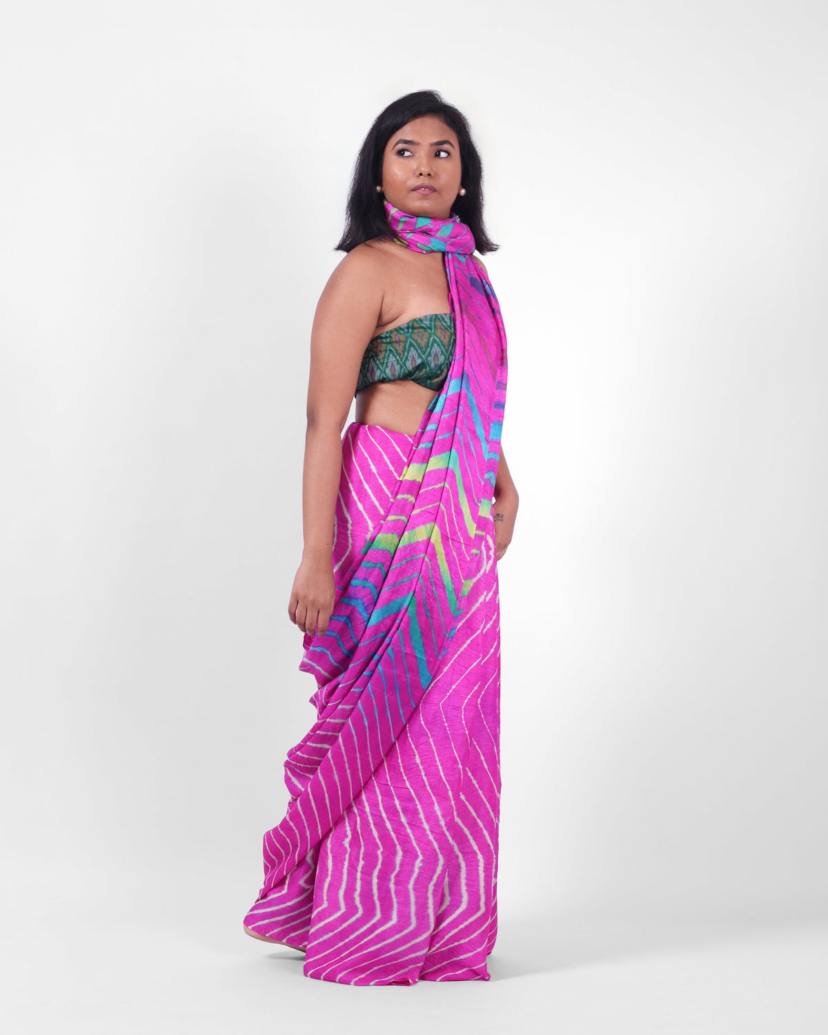 A model is wearing a pink leheriya saree in tussar, the pallu is draped like a stole around her neck. The body of the saree is a pink and white leheriya with a multicolour leheriya on pallu. 