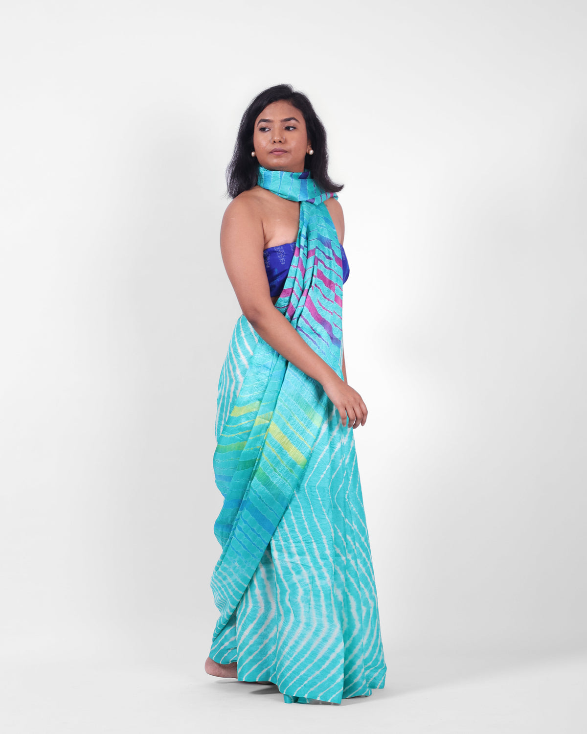 A model wearing a turquoise blue leheriya saree in tussar, with the pallu styled as a stole around her neck. 