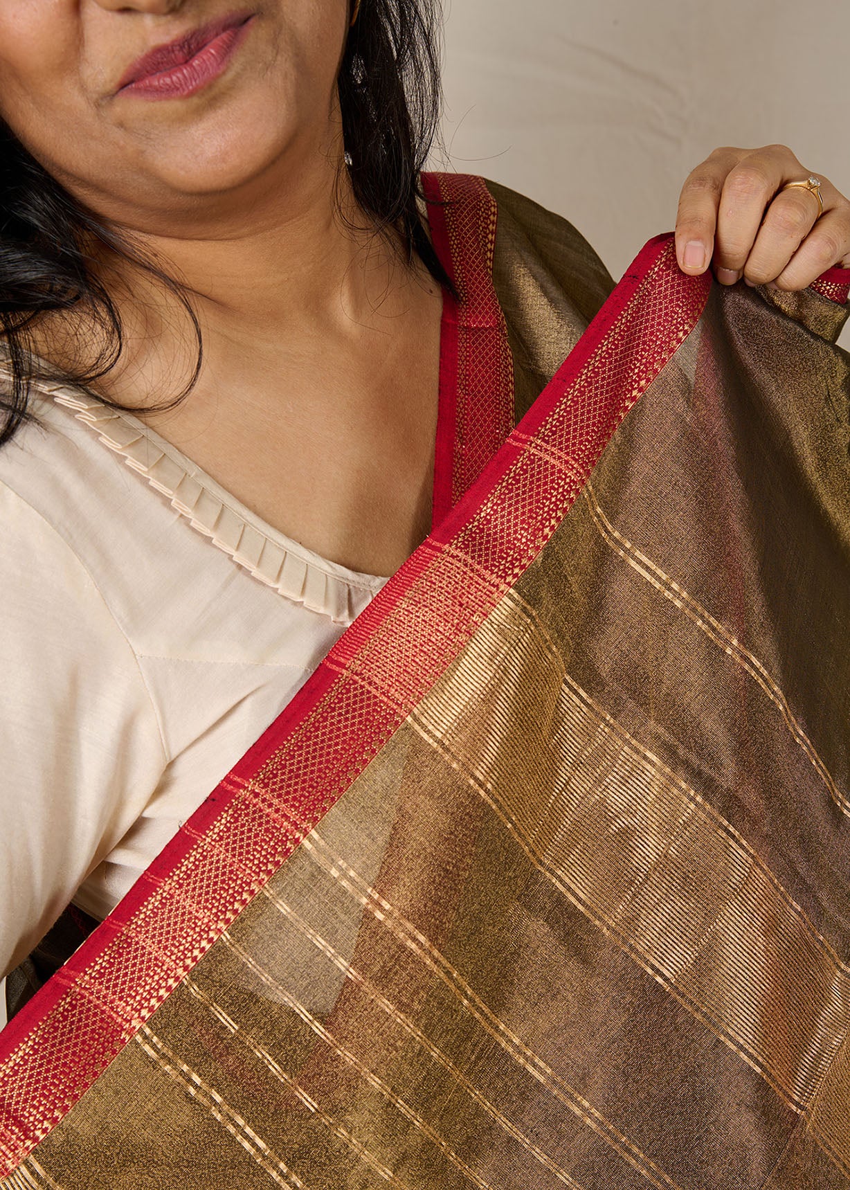 Women wearing a maheshwari tissue saree in dual tone of black and gold showcasing the ornate border of the saree.