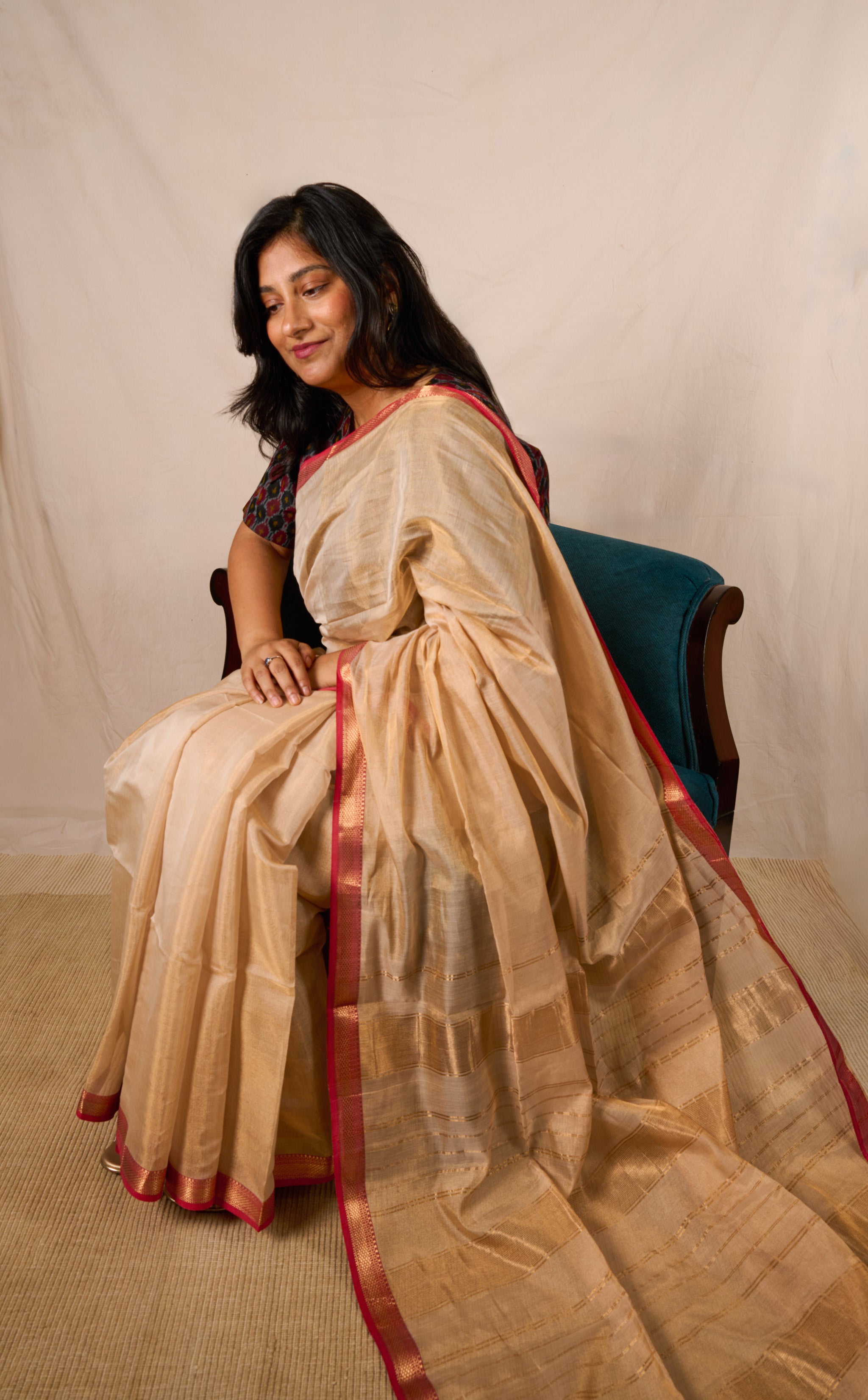 Model seated on an accent chair in a maheshwari tissue saree