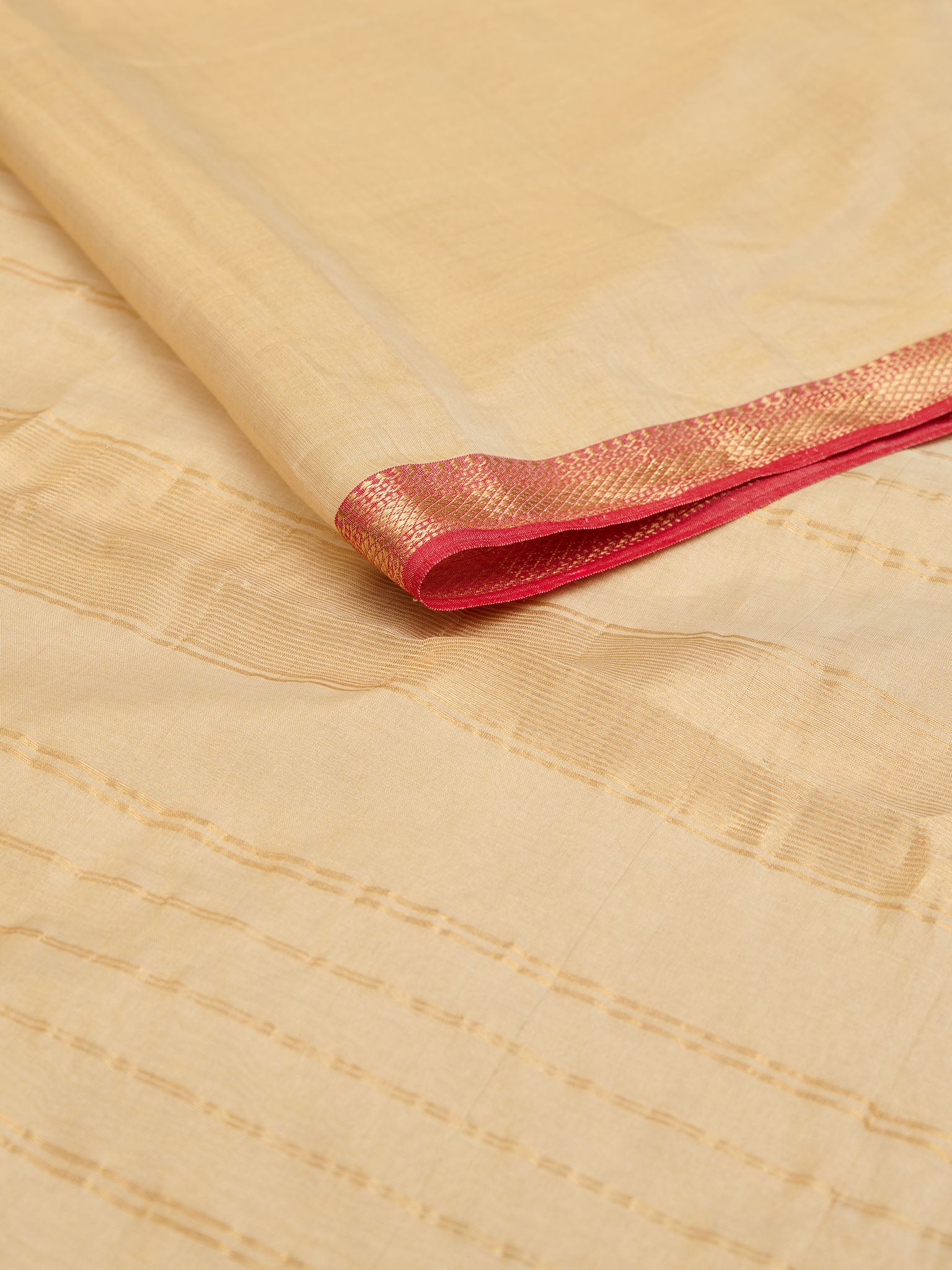 Maheshwari tissue saree in ivory with red traditional border laid out beautifully