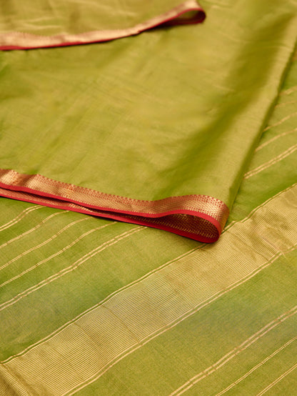 A maheshwari tissue saree in dual tone of light green and gold on display on a flat surface.
