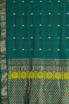 Teal green Assam cotton saree with an ornate zari border and traditional motifs on display.