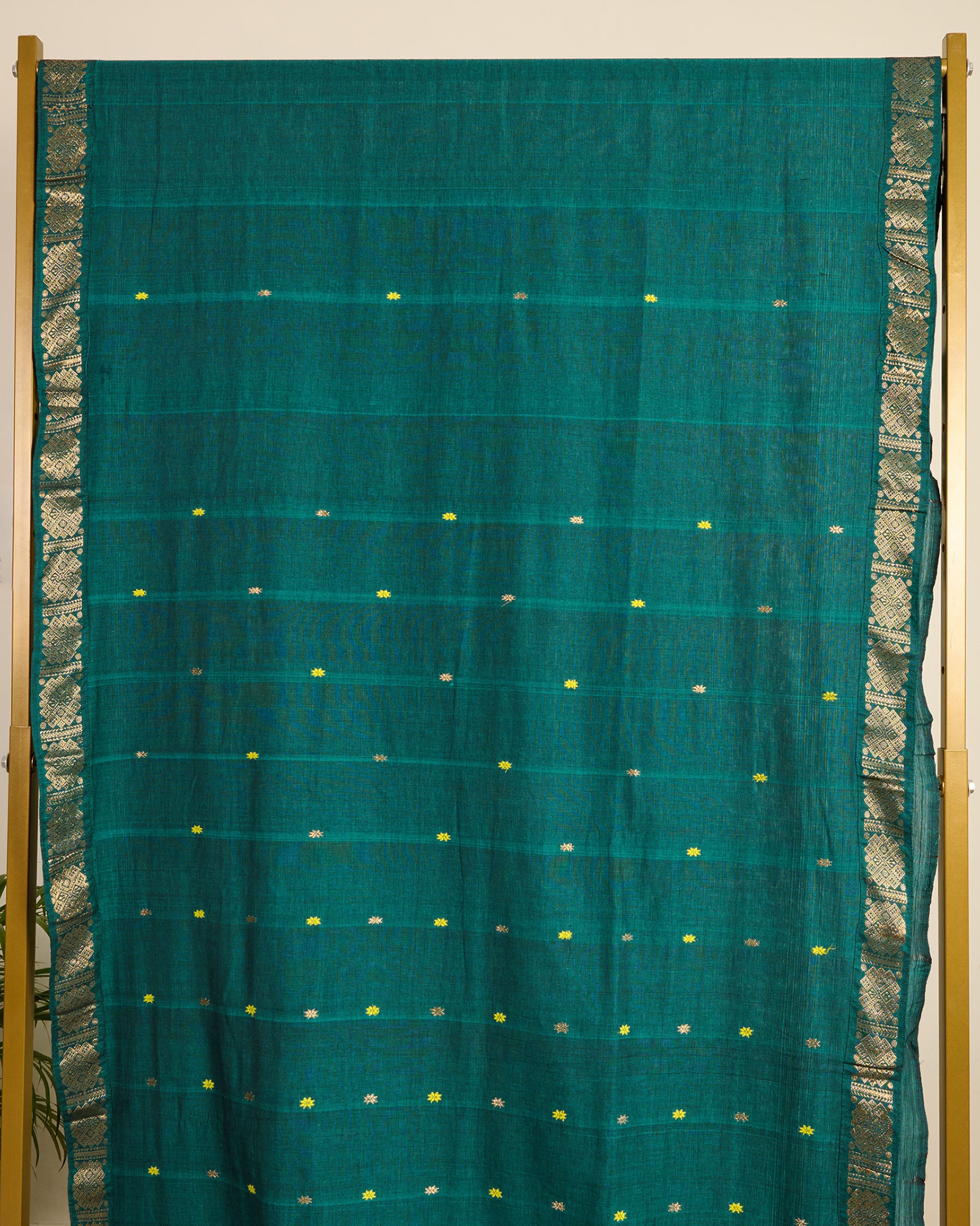 Assam cotton saree in teal green colour with traditional motifs and ornate zari border on display.