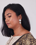 Model wearing a classic and clean design of silver ball drop earrings on her left ear. 