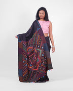 Model showcasing a black saree with colourful Lambani embroidery with an ornate pallu draped in the front. 