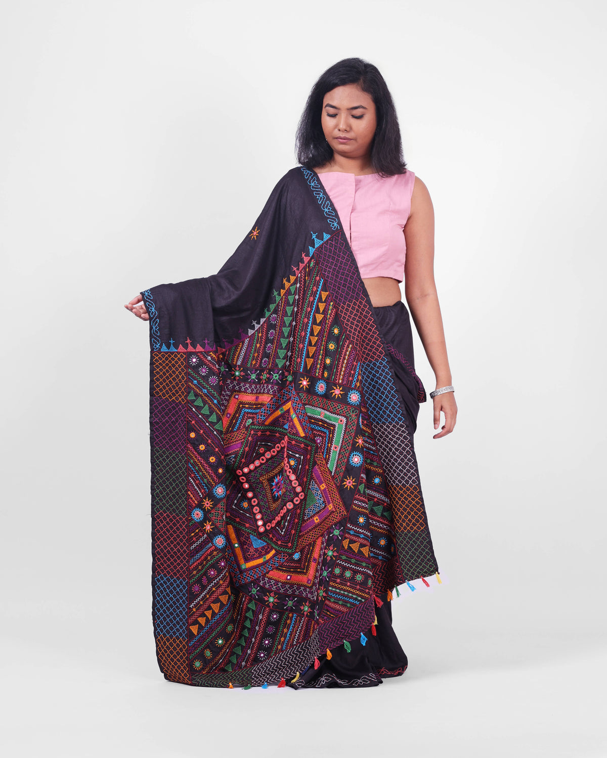 Model showcasing a black saree with colourful Lambani embroidery with an ornate pallu draped in the front. 