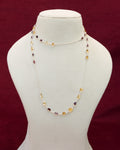 A long neck chain with faceted citrine and garnet semi precious gemstones set in 92.5 silver layered on a manequin. 