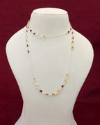 A long neck chain with faceted citrine and garnet semi precious gemstones set in 92.5 silver layered on a manequin. 