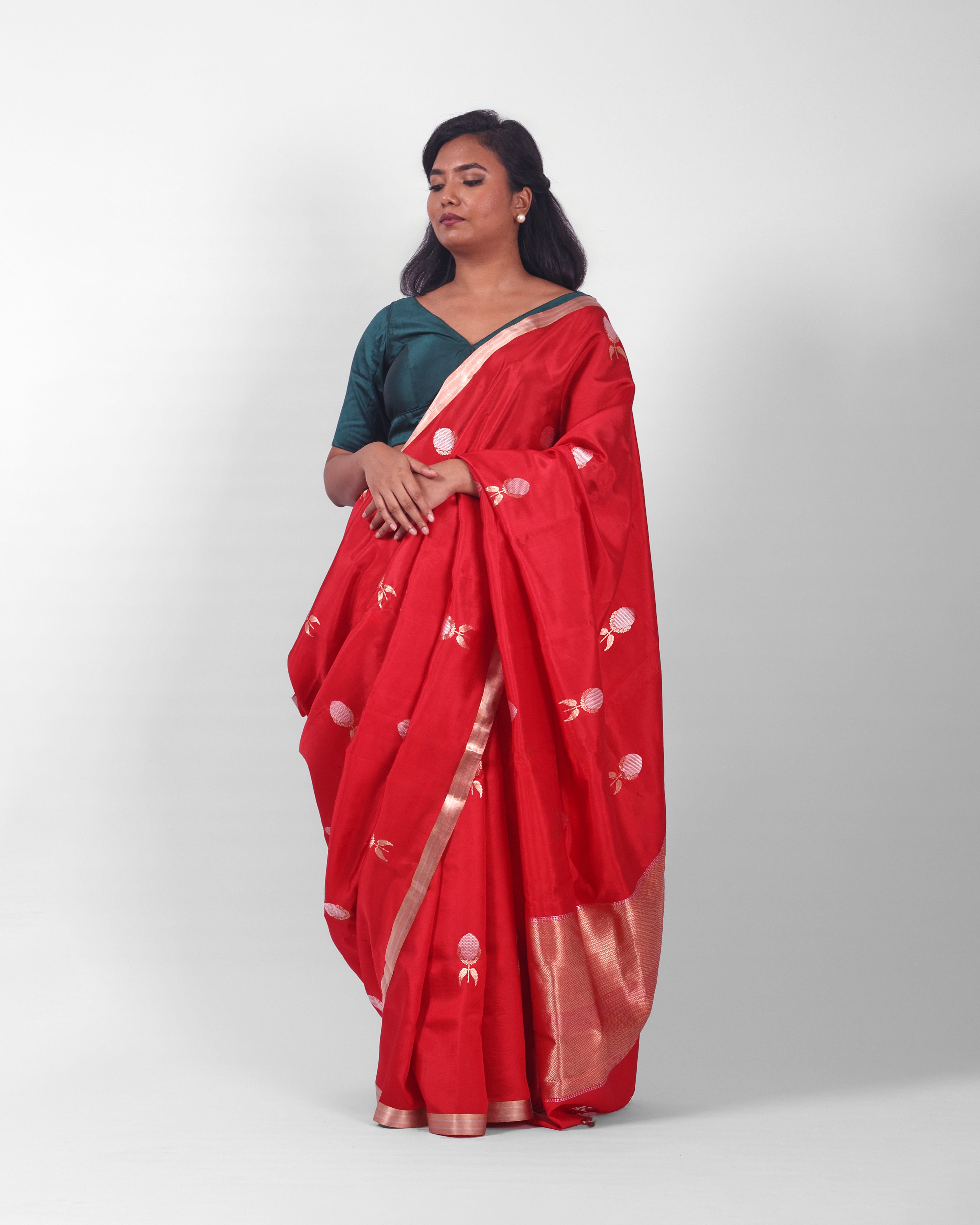 A female model showcasing a bright red silk kadwa banarasi saree with golden and silver zari border and kadwa floral motifs all over the saree. 
