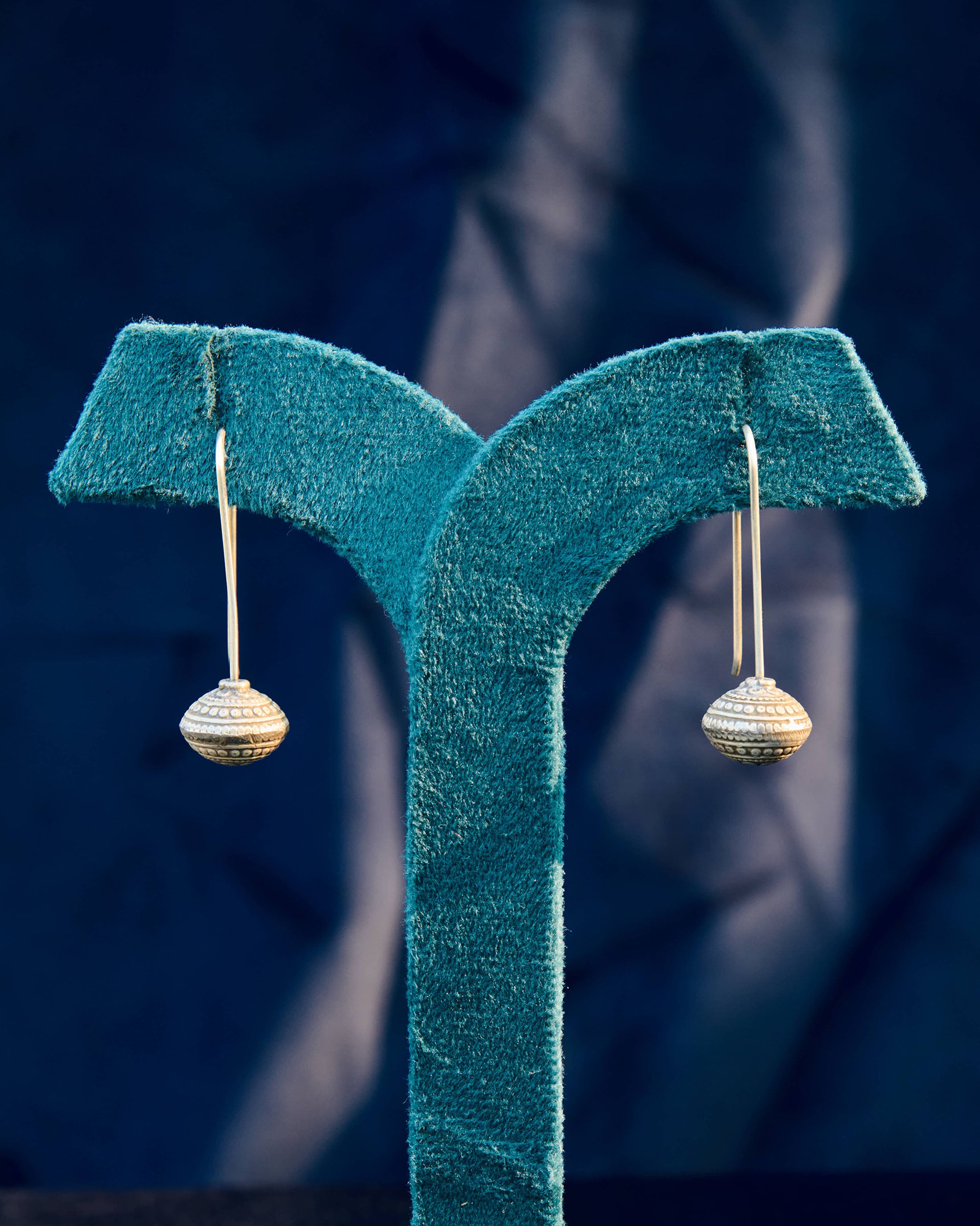 Avira silver ball drop earring on a display stand