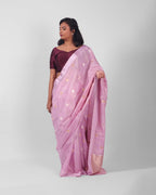 A woman modeling a lilac silk kadwa banarasi saree with small gold floral motifs  with red minakari in the centre all over he saree. 

