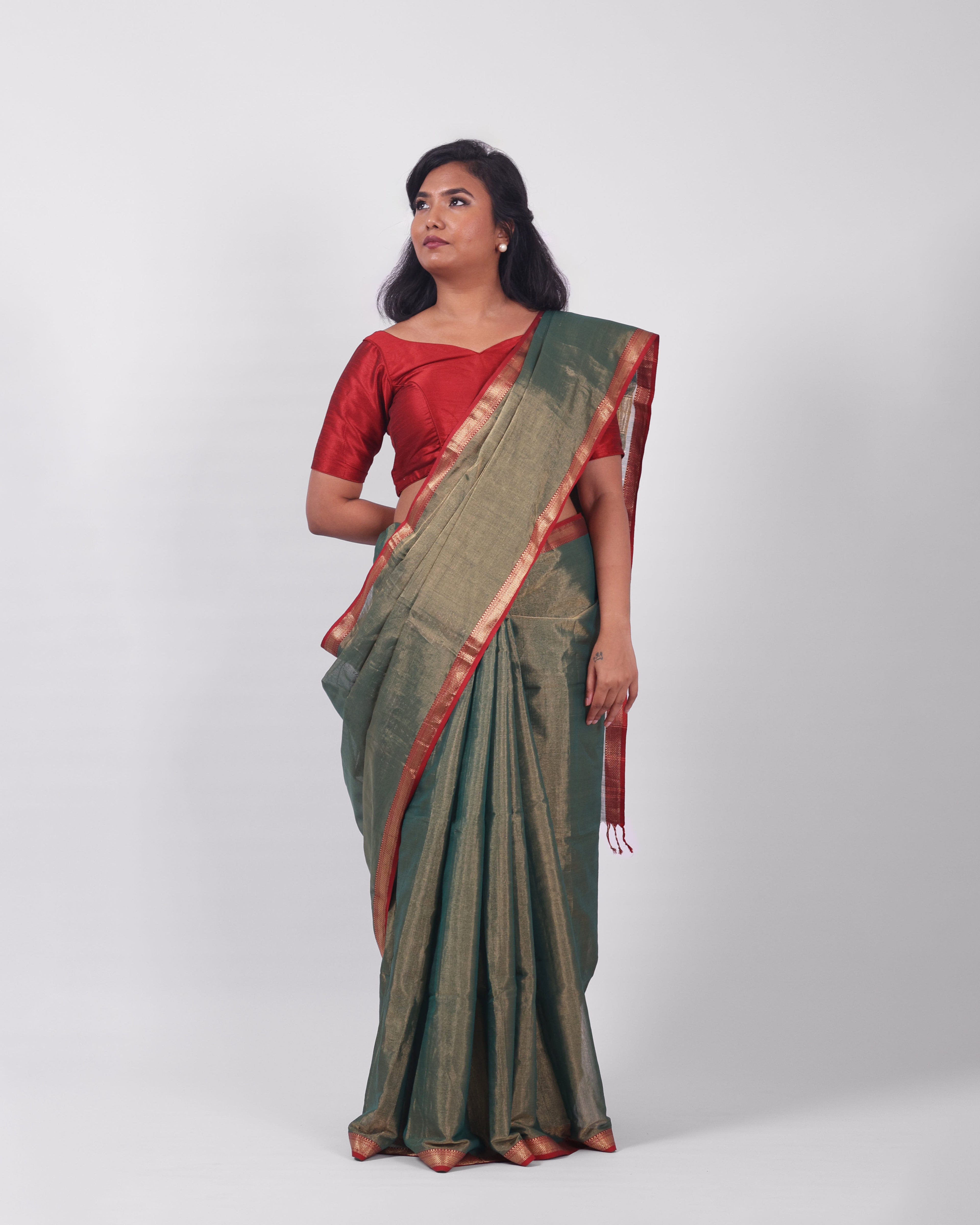 A model wearing our tissue silk maheshwari saree in the colour dark green, with a traditional chasm-e-bulbul (diamond) border of maheshwari weaves. 