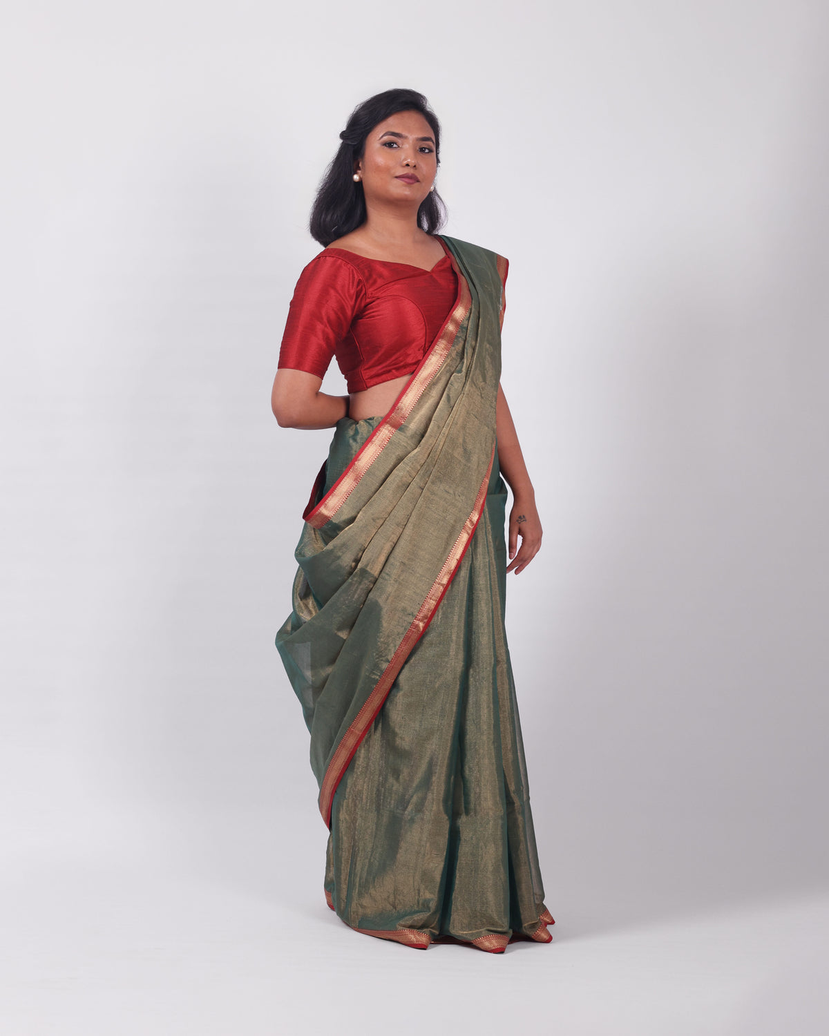 A model wearing our tissue silk maheshwari saree in the colour dark green, with a traditional chasm-e-bulbul (diamond) border of maheshwari weaves. 