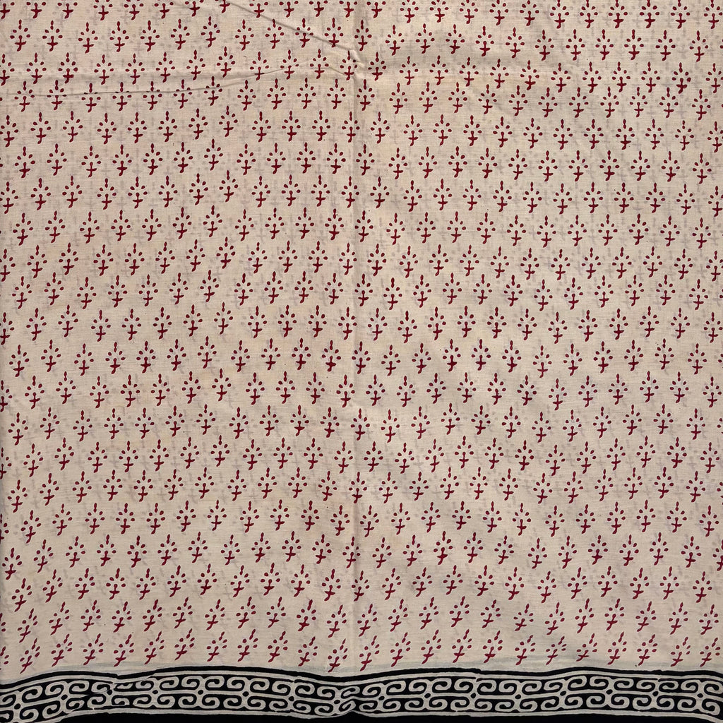 Beige coloured base fabric cotton saree with red booti and black border.