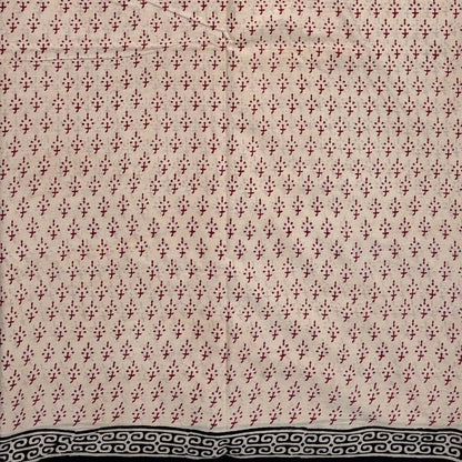 Beige coloured base fabric cotton saree with red booti and black border.