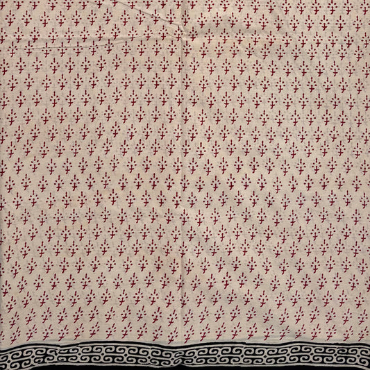 Beige coloured base fabric cotton saree with red booti and black border.