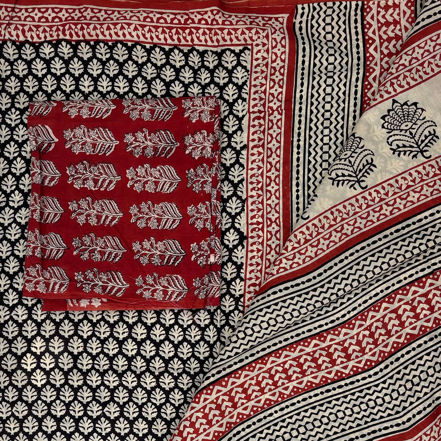 Black base colour cotton blockprinted saree with beige booti and red border and contrasting red blockprinted blouse material.