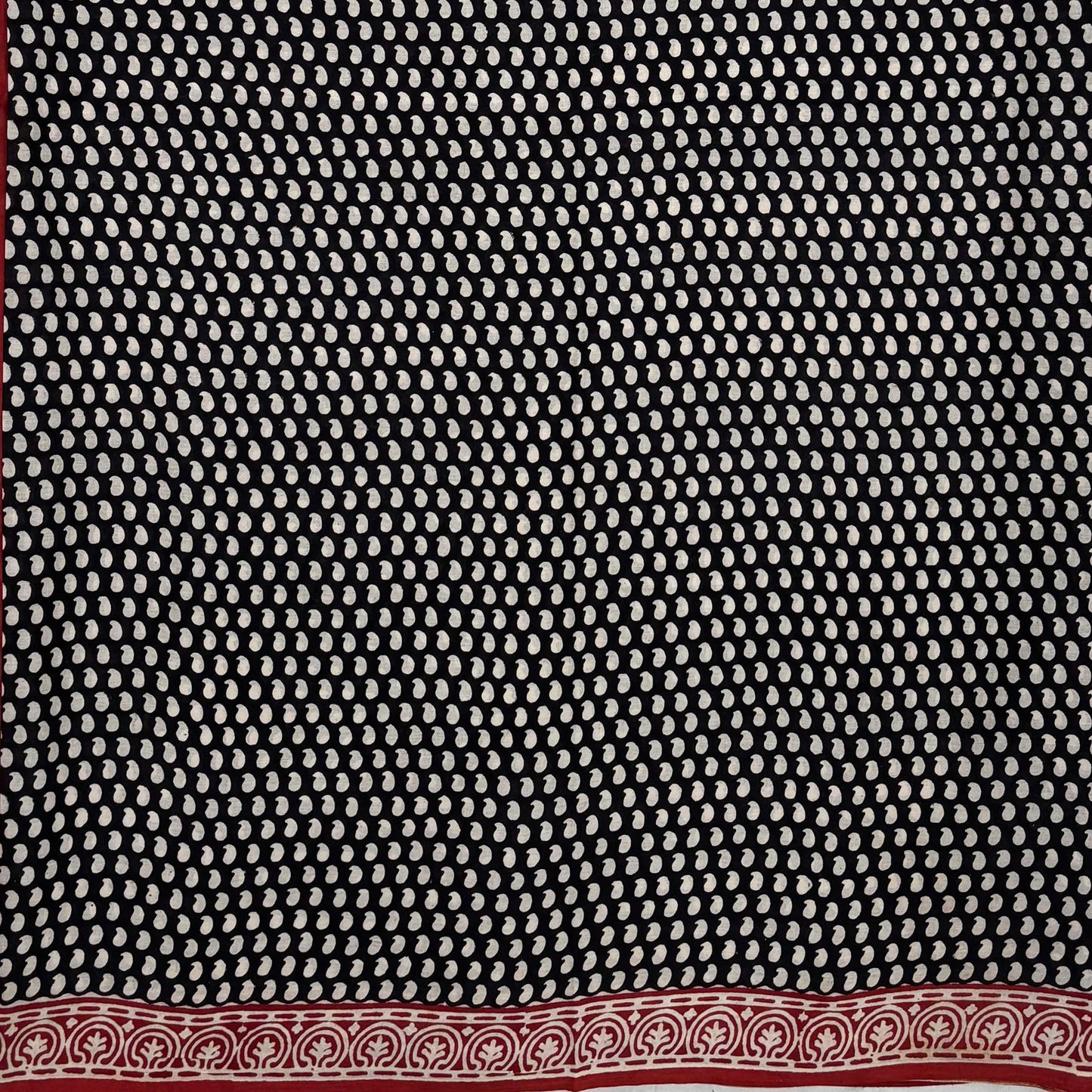 Black base colour cotton block printed saree with small beige paisley booti all over and red border.