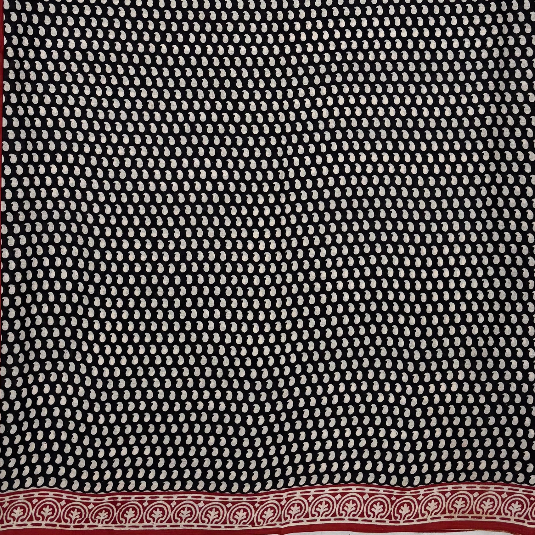 Black base colour cotton block printed saree with small beige paisley booti all over and red border.