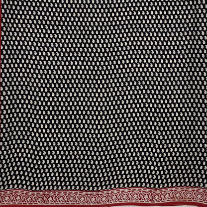 Black base colour cotton block printed saree with small beige paisley booti all over and red border.