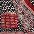 Black base colour cotton saree with all over small beige paisley blockprint, red border and a contrasting red blockprinted blouse material. 