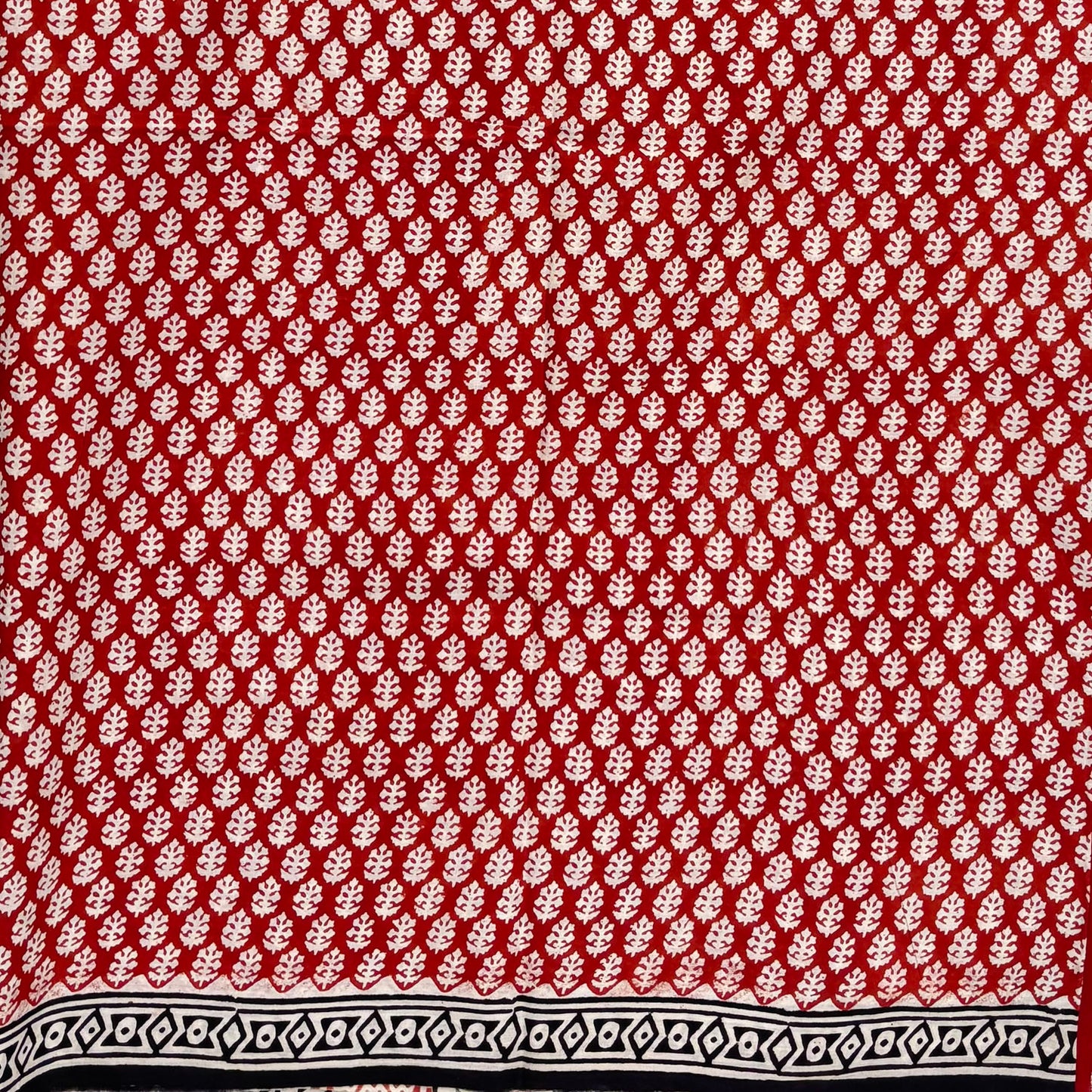 Red base colour cotton block printed saree with all over floral beige booti and black border.