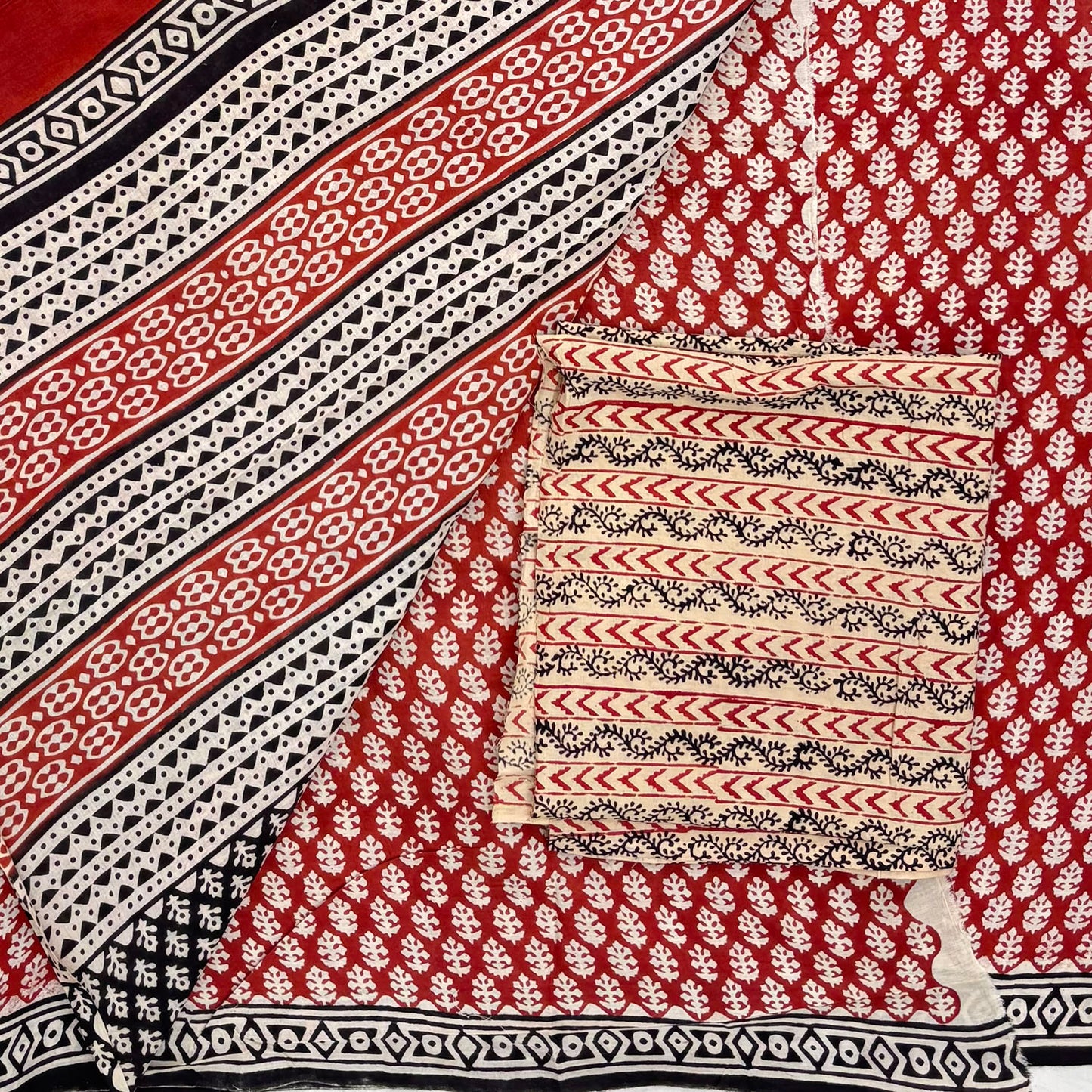 Red base colour cotton block printed saree with small beige floral booti all over, contrasting beige blockprinted blouse material and pallu on display.