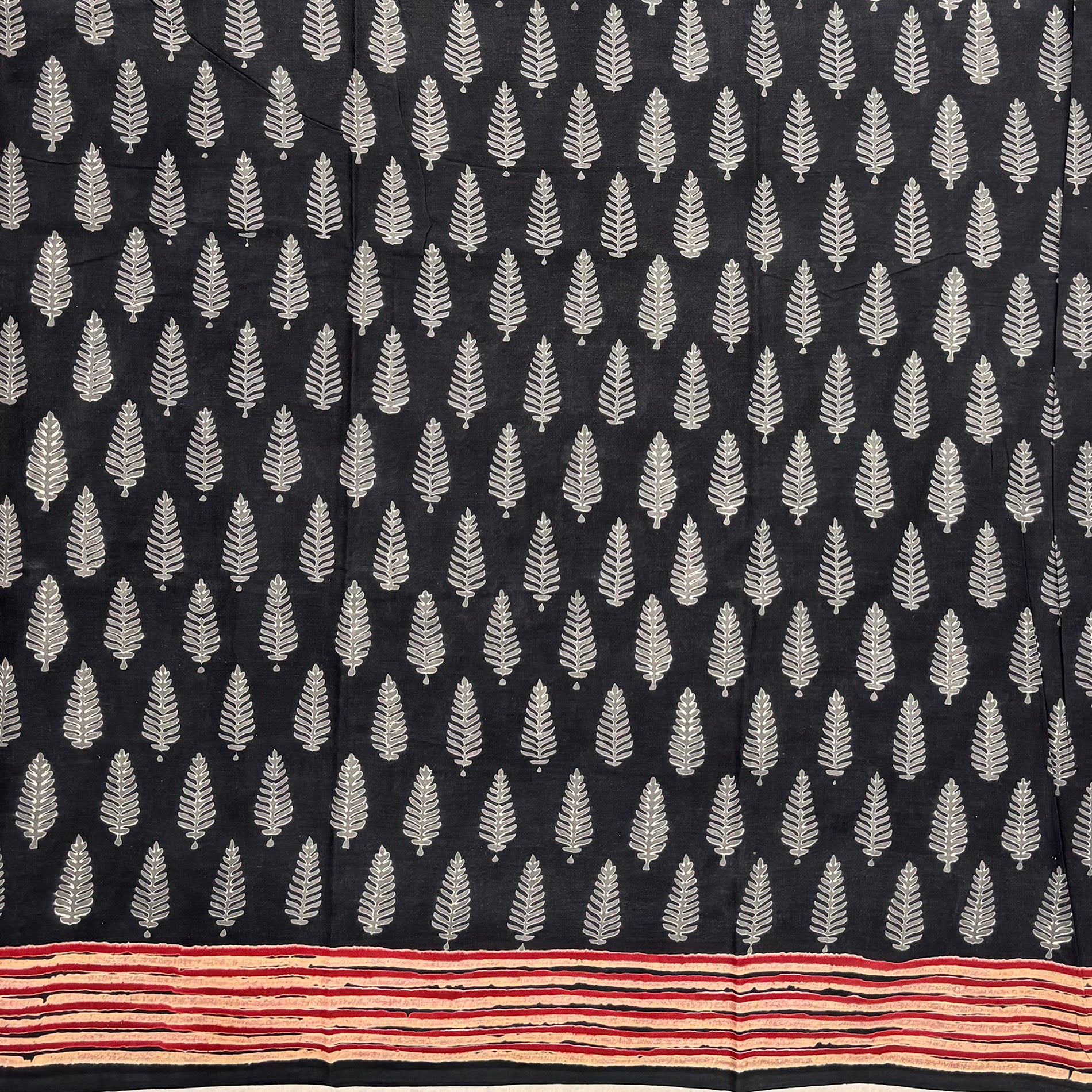 Charcoal grey base cotton saree with white leaf booti block print and red border.